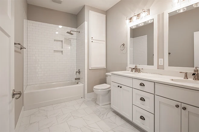 A white bathroom remodeled with subway tile shower and double vanity
