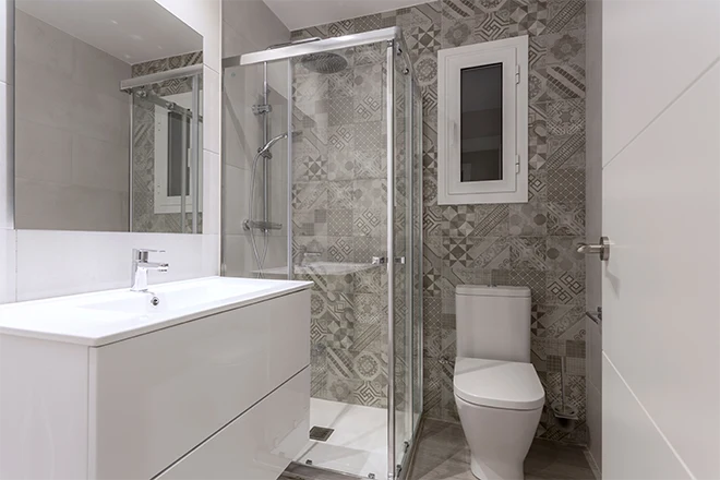 Small bathroom with geometric tiles and a glass shower and a white vanity